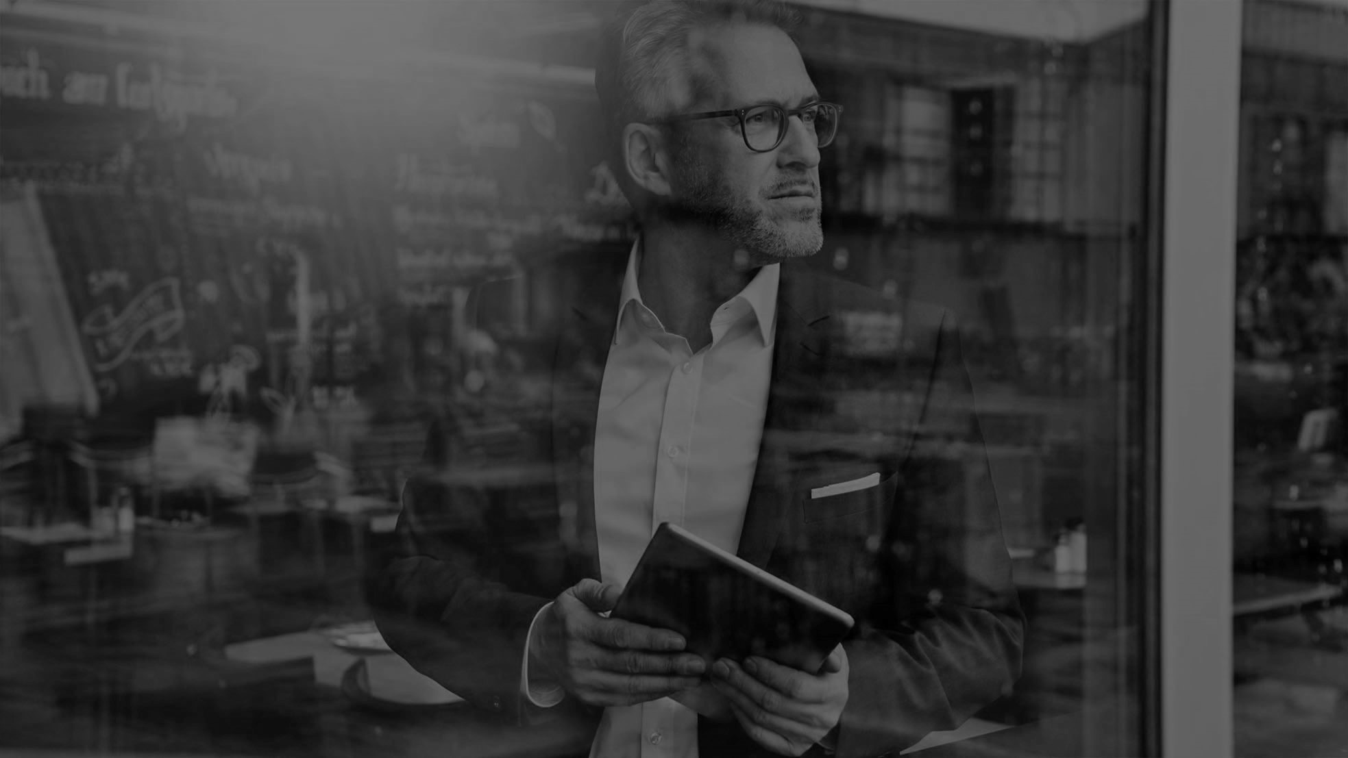An advisor at an office window, tablet in hand